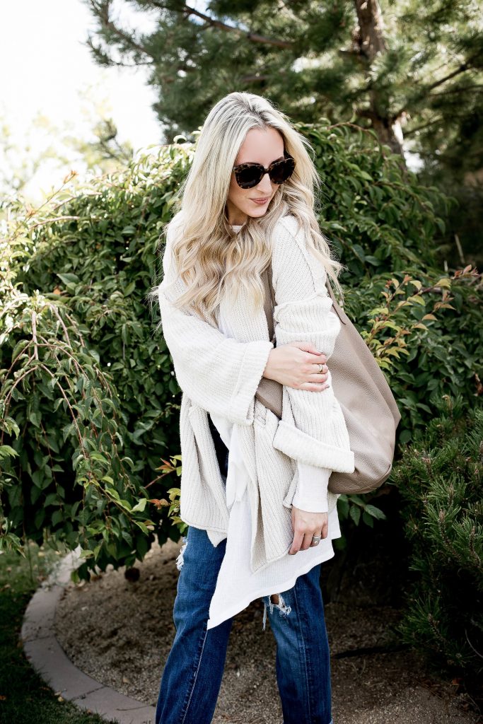 Emily Farren Wieczorek of Two Peas in a Prada wears a cozy cream cardigan from free people, with karen walker suglasses, a cuyana tote, and boyfriend jeans. 