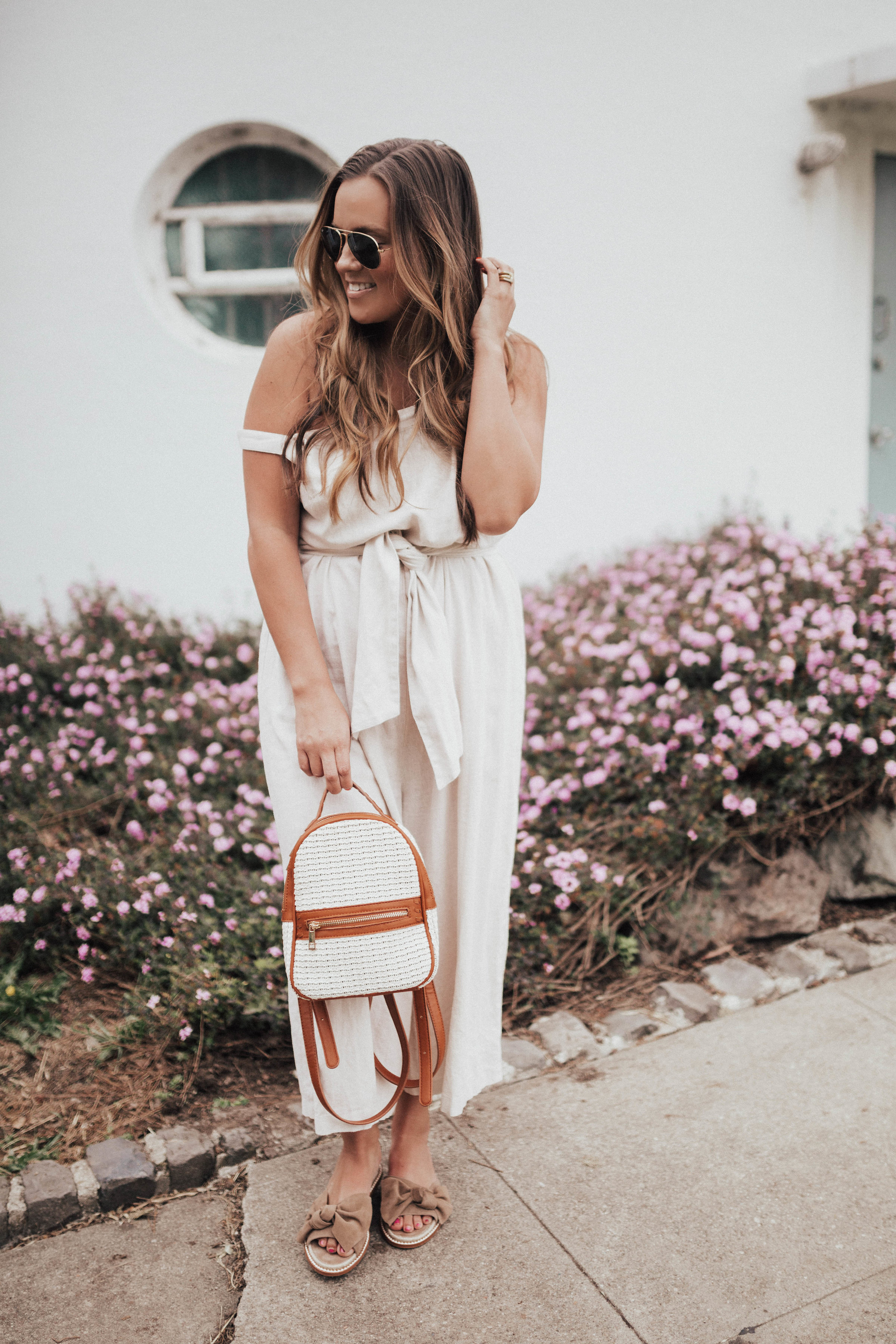 Ashley Zeal from Two Peas in a Prada wears a beige BP linen jumpsuit from Nordstrom that is under $60. She is wearing Caslon sandals and Sole Society bag. 