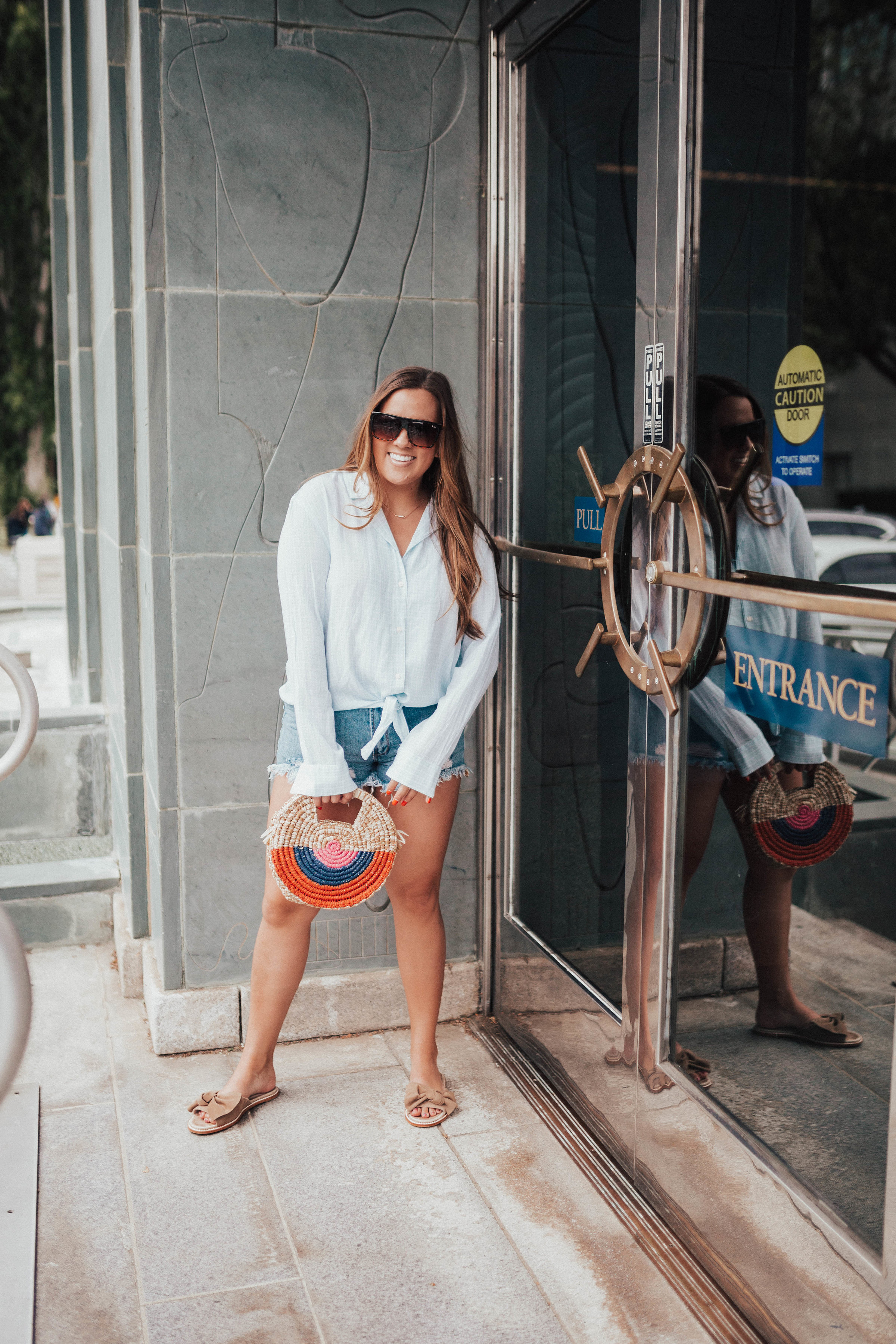 Ashley Zeal from Two Peas in a Prada pairs a tie front shirt and jean shorts for a nautical vibes outfit. 