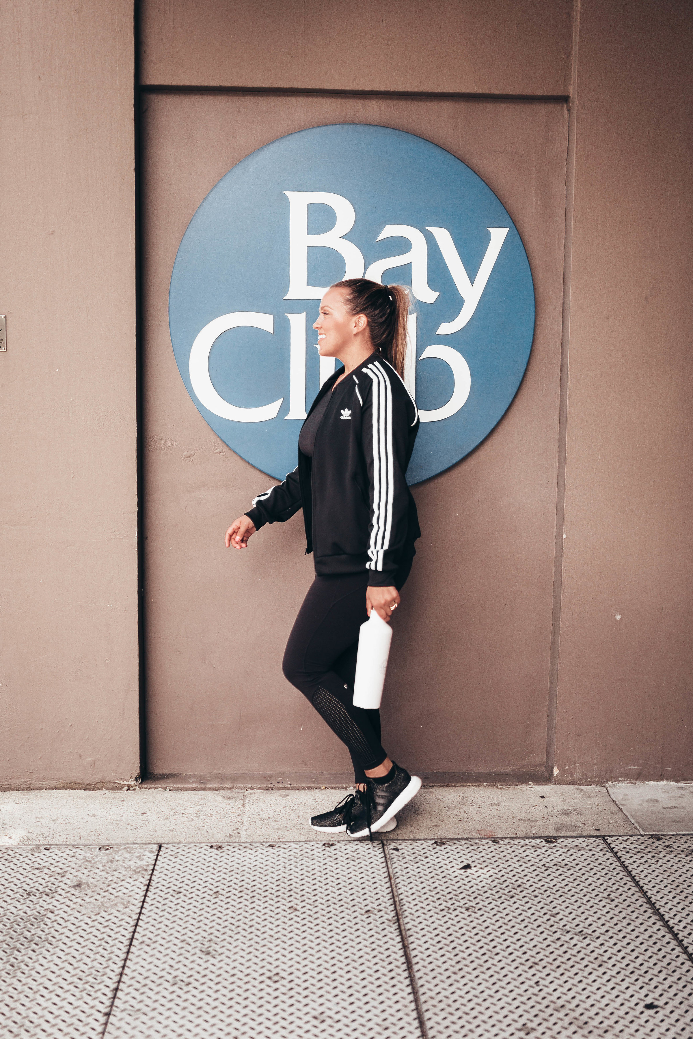 Ashley Zeal from Two Peas in a Prada shares a six month review of Bay Club San Francisco. She is wearing Splits 59 leggings and an Adidas jacket and sneakers. 